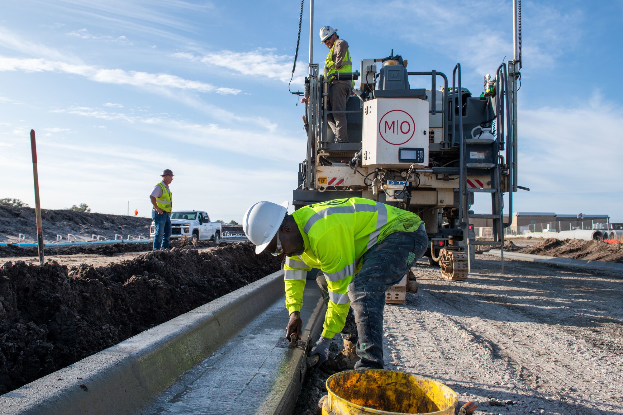 A contractor uses trowels to smooth a cement curb.