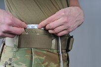 An Airman measures his waist with a tape measure