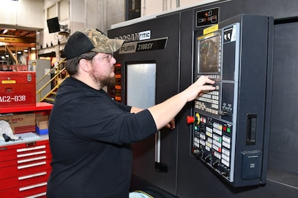 A man operates a computerized manufacturing machine.