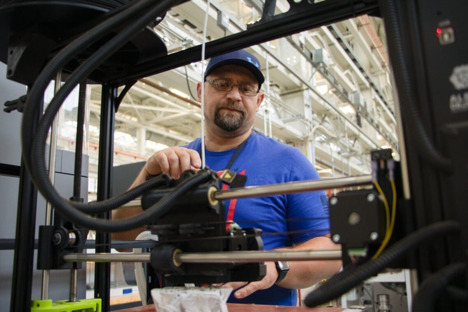 A man stands near a manufacturing machine.