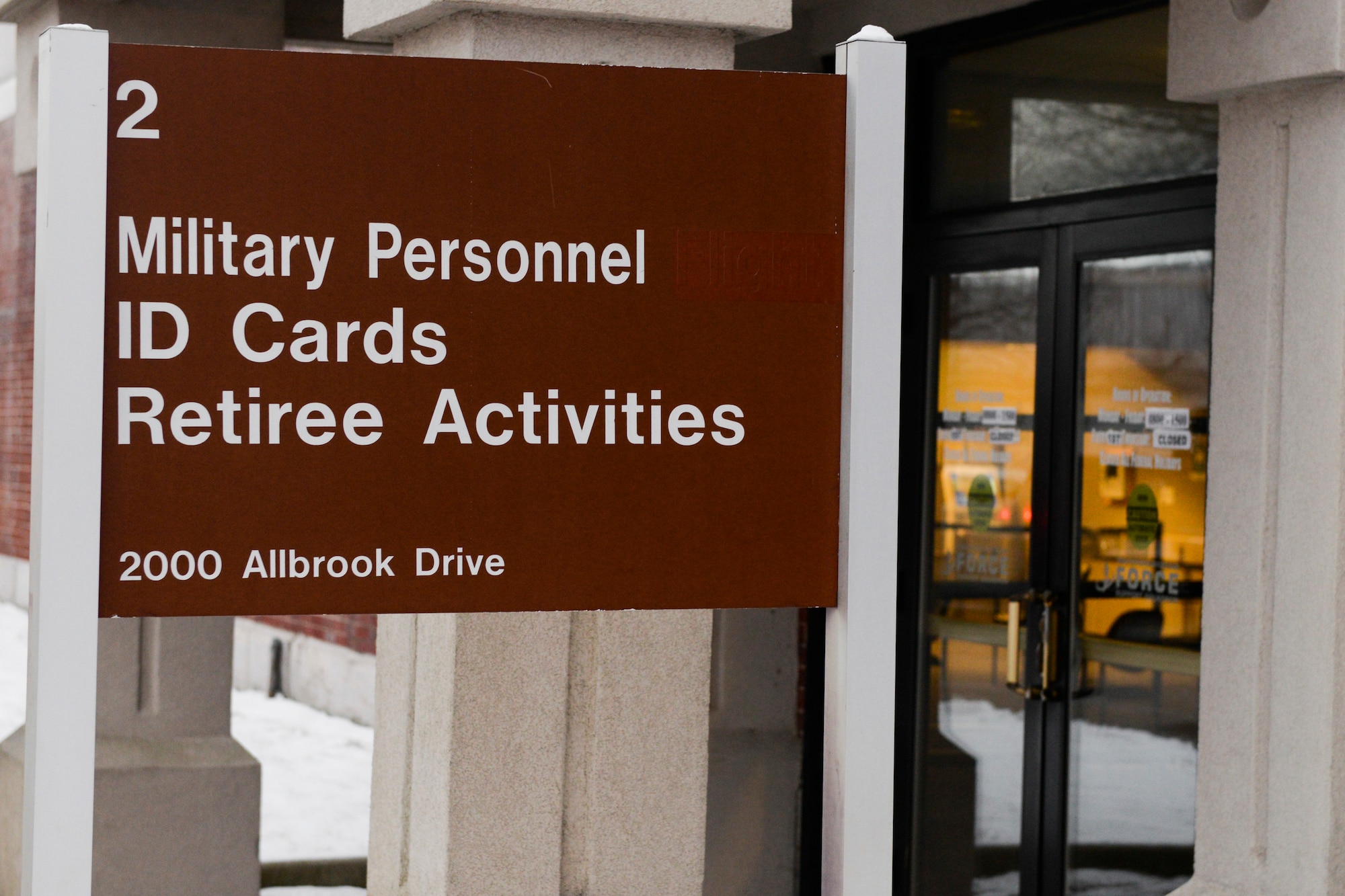 A sign outside a military building indicates: "Military Personnel ID Cards Retiree Activities."