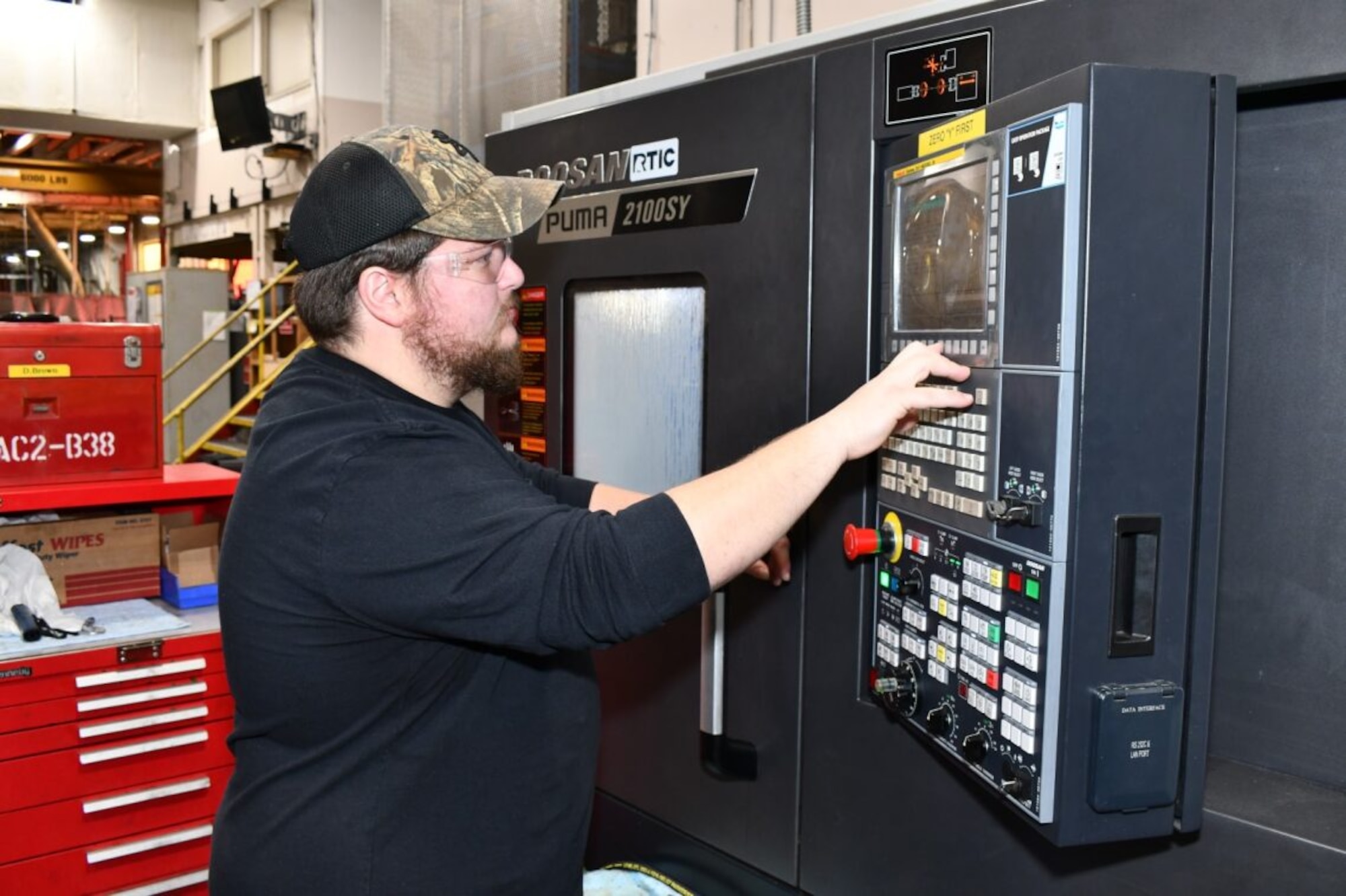 A man operates a computerized manufacturing machine.