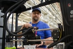 A man stands near a manufacturing machine.