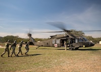 Airmen approach a UH-60 on Dec. 6, 2023, at Joint Base San Antonio-Camp Bullis, Texas, during Operation AGILE Medic. This joint force medical training exercise immerses medics in the seamless process of transporting patients from the Expeditionary Medical Support unit to the En Route Patient Staging System team, and onwards to Air Evacuation and Critical Care Air Transport Teams, and vice versa. The hands-on experience ensures medics gain a comprehensive understanding of communication protocols, the critical timing for patient preparation, and the intricacies of the entire process. (U.S. Air Force photo by Senior Airman Melody Bordeaux)