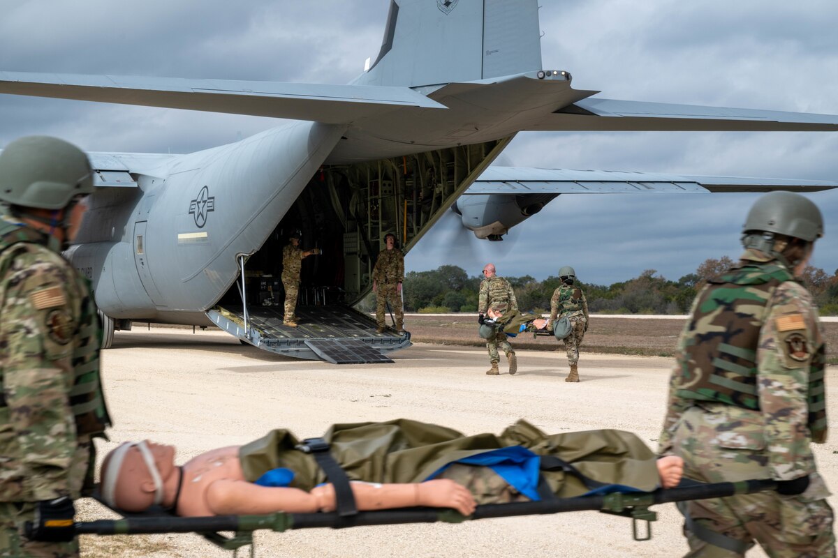 Airmen transfer simulated patients to a C-130 on Dec. 7, 2023, at Joint Base San Antonio-Camp Bullis, Texas, during Operation AGILE Medic. The joint force medical training exercise equipped medics with training in various austere environments, both on-ground and in-air. (U.S. Air Force photo by Senior Airman Melody Bordeaux)