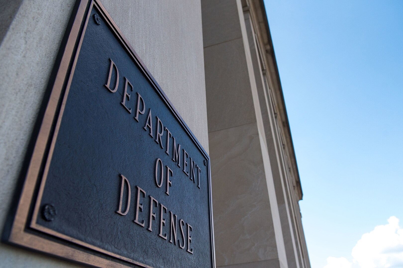 A metal plate hanging on a building column says "DEPARTMENT OF DEFENSE."