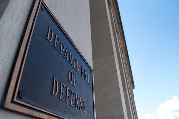 A metal plate hanging on a building column says "DEPARTMENT OF DEFENSE."