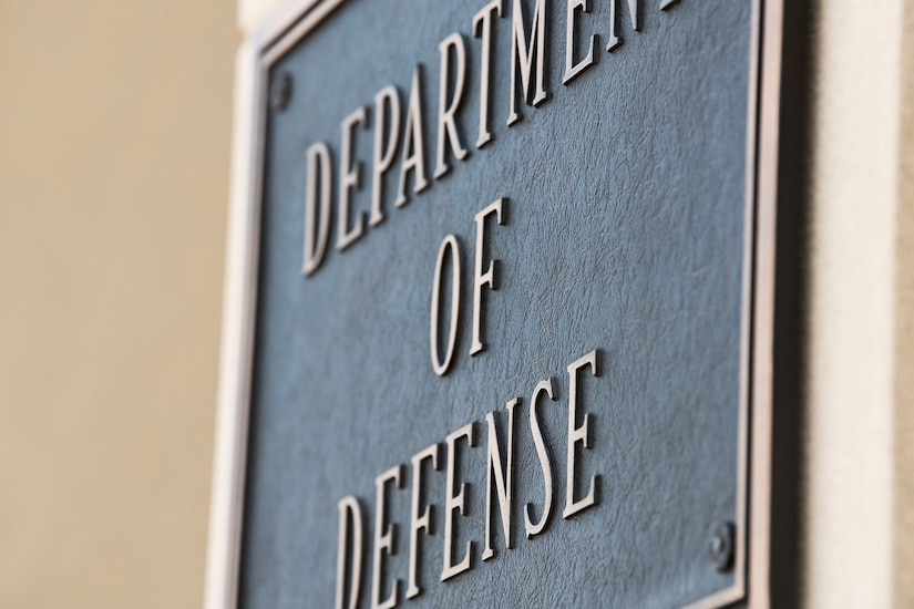 A metal plate hanging on a building says "DEPARTMENT OF DEFENSE"