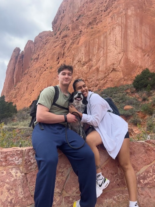 A man and woman pose with their dog for a photo.