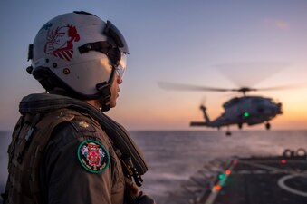 Lt. Cmdr. Aric McGee, observes an MH-60R Sea Hawk, assigned to the “Warlords” of Helicopter Maritime Strike Squadron (HSM) 51, land on the flight deck of Arleigh Burke-class guided-missile destroyer USS Hopper (DDG 70).