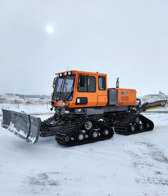 A tracked vehicle sits in an icy parking lot.