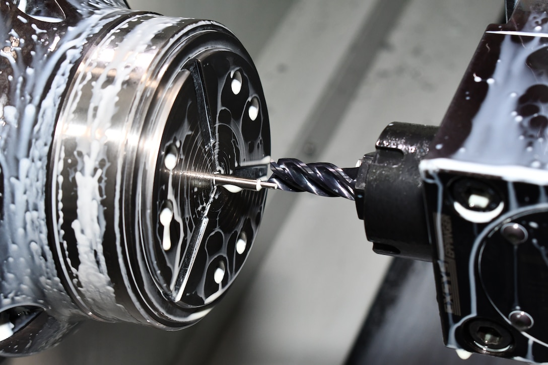 A lathe is photographed while manufacturing a part.