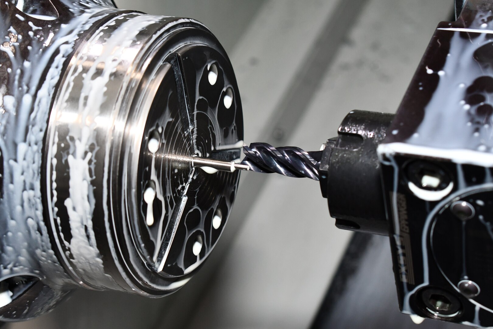 A lathe is photographed while manufacturing a part.