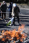 A visitor disposes of his “kadomatsu,” a pine tree stalk displayed at the entrance of one’s home, by tossing it in a fire as part of the “Dondo Yaki” ceremony held Jan. 14 at Kanigasawa Park near Camp Zama, Japan. Also seen are visitors roasting “dango,” small dumplings made of sticky rice, which they eat to bring good health in the New Year.