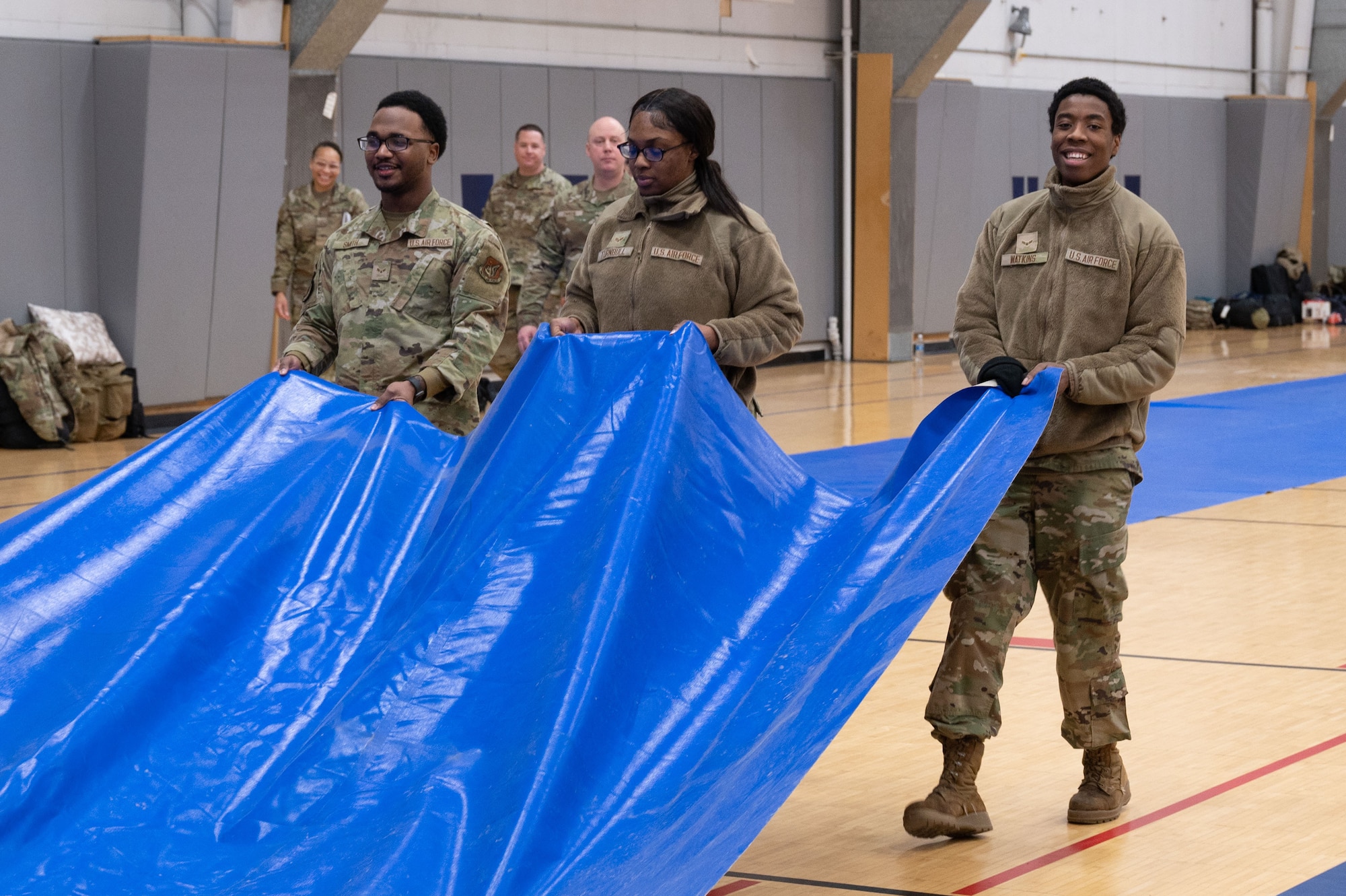 Airmen assigned to the 354th Force Support Squadron pull out a mat to cover the gymnasium floor during Raven Beddown 2024 on Eielson Air Force Base, Alaska, Jan. 6, 2024.