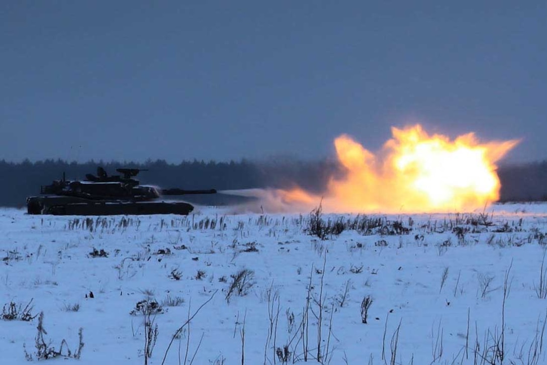 A tank fires a shell in a snowy field against a darkish sky.