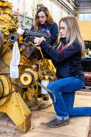 Hannah Honeycutt, mechanic helper, and Janelle Sorensen, heavy mobile equipment mechanic apprentice, Code 730, Crane Maintenance, perform valve adjustment checks on an engine. (U.S Navy Photo by Wendy Hallmark)