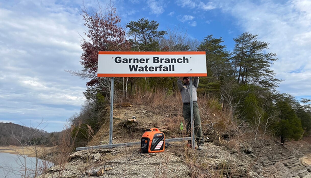 Park Ranger Dylon Norton installs a new sign for Garner Branch Waterfall Nov. 20, 2023, on the shoreline of Lake Cumberland in Monticello, Kentucky, in Wayne County. (USACE Photo by Cody Pyles)