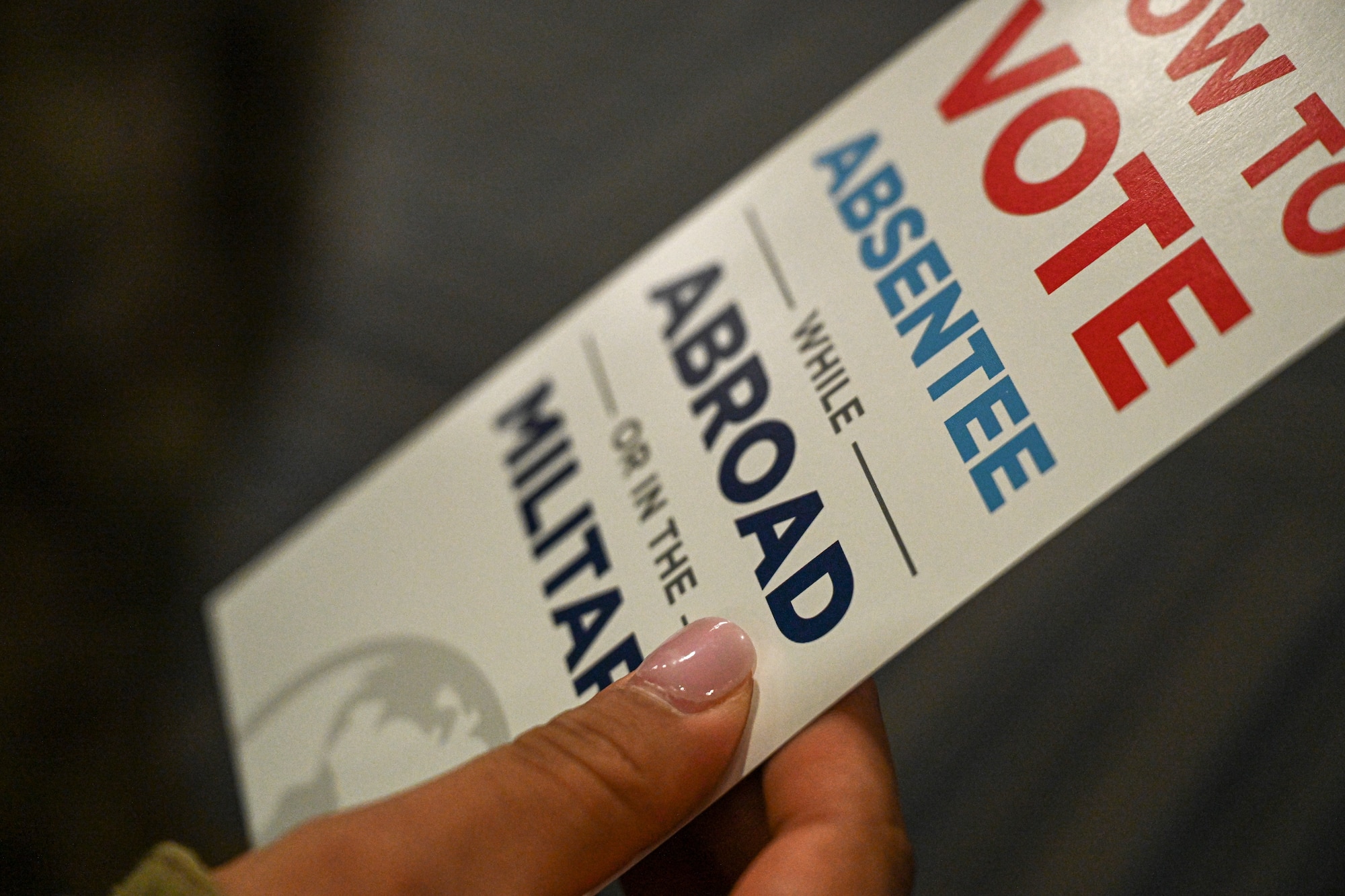 A pamphlet about absentee voting is displayed in someone's hand.
