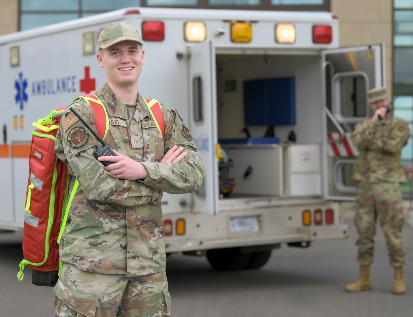 Air Force emergency medical technician stands in front of the back of an ambulance