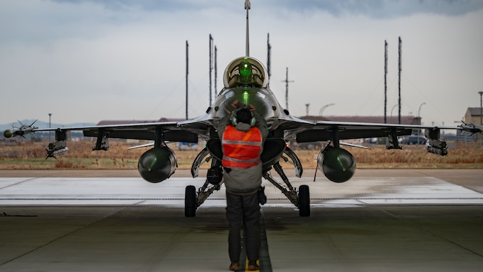 A member of the 80th Fighter Generation Squadron marshals an F-16 Fighting Falcon for hot pit refueling.