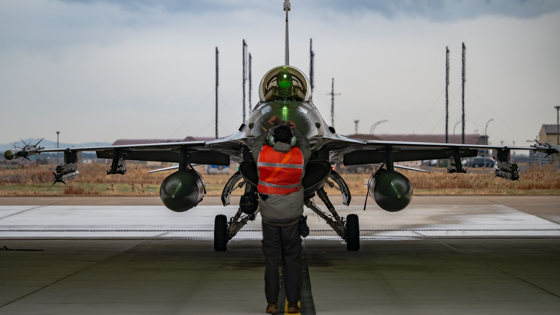 A member of the 80th Fighter Generation Squadron marshals an F-16 Fighting Falcon for hot pit refueling.