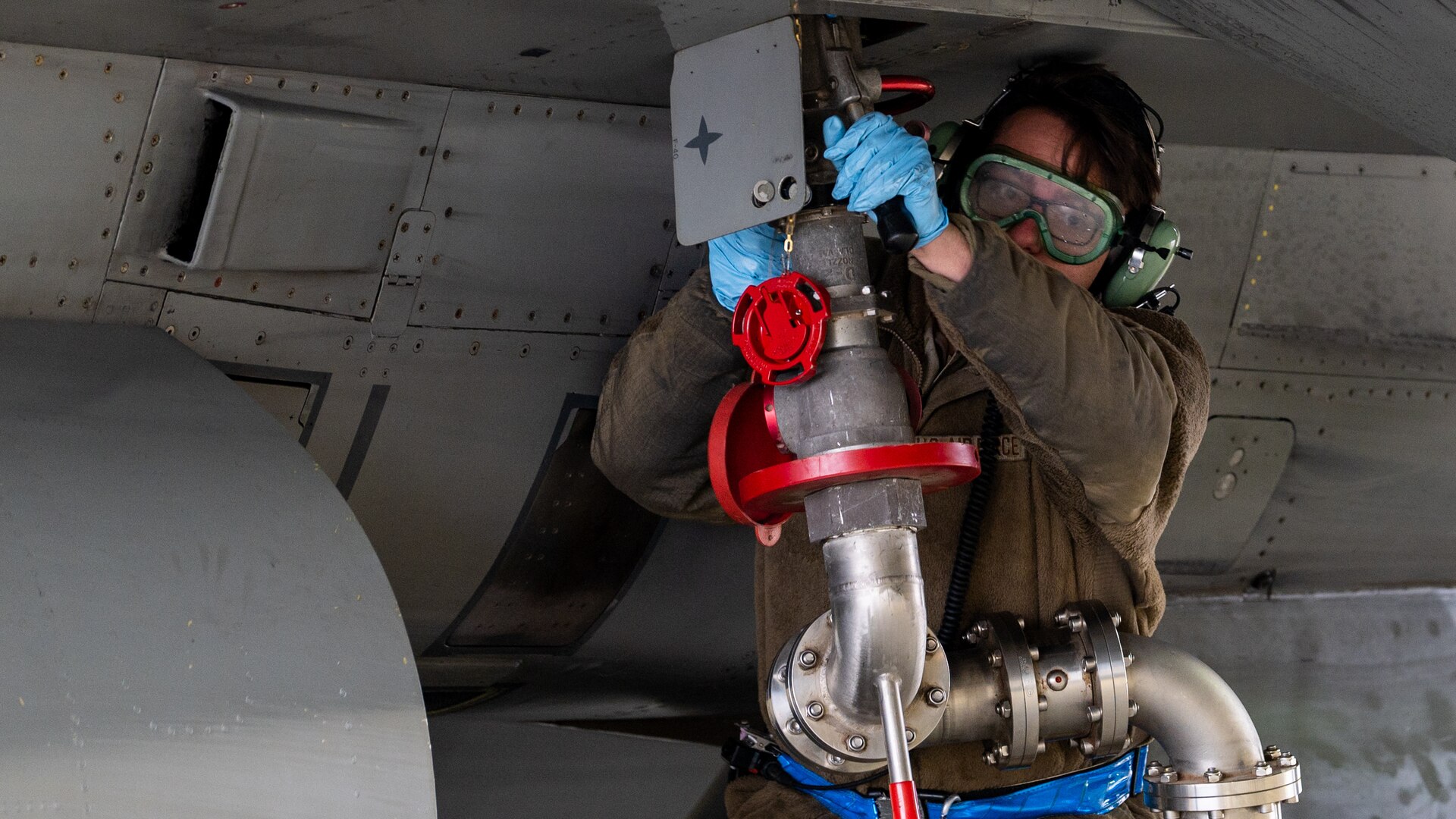 Senior Airman Robert Klassen attaches a fuel hose to refuel the aircraft during a routine hot pit refueling.