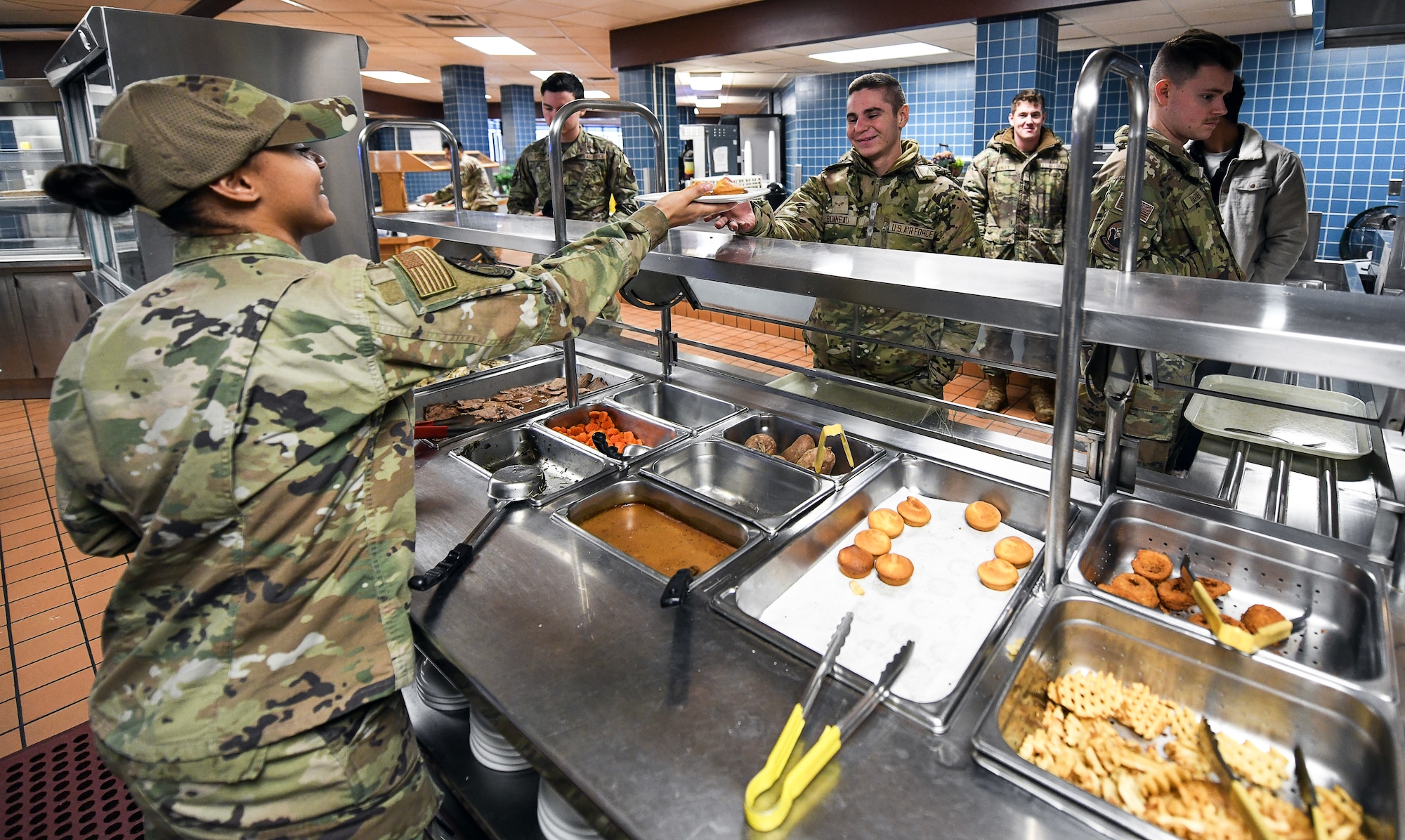 an airman hands prepared food over the counter to another airman.