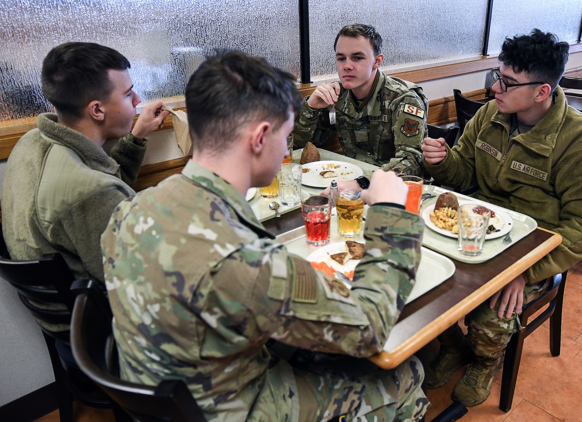 Four uniformed personnel eating lunch at the dining facility.