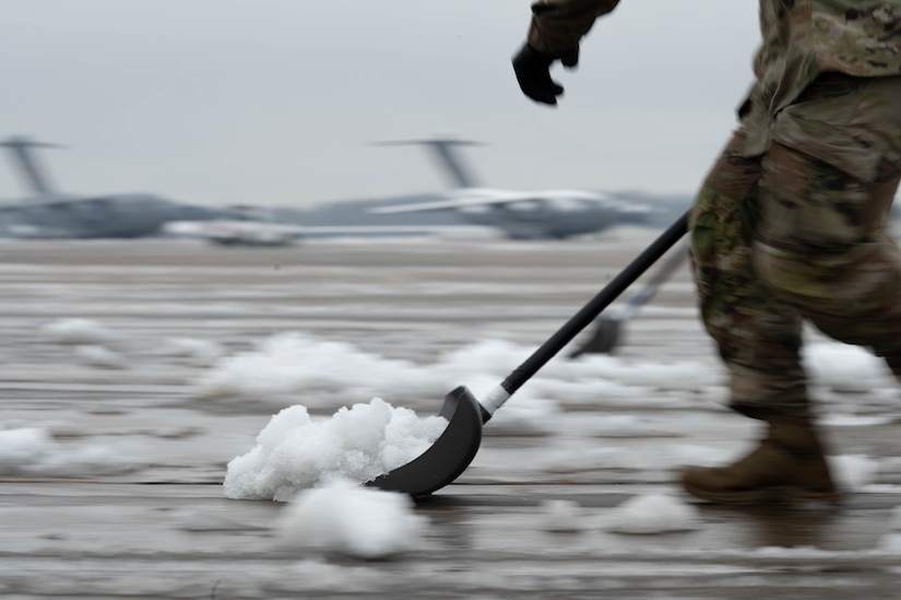 A U.S. Air Force Airman assigned to the 305th Air Mobility Wing shovels snow on the flightline during a winter storm at Joint Base McGuire-Dix-Lakehurst, N.J., Jan. 16, 2024. Airmen assigned to various JB MDL squadrons maneuvered through harsh conditions to keep the mission going despite several base closures due to safety concerns. (U.S. Air Force photo by Airman 1st Class Aidan Thompson)