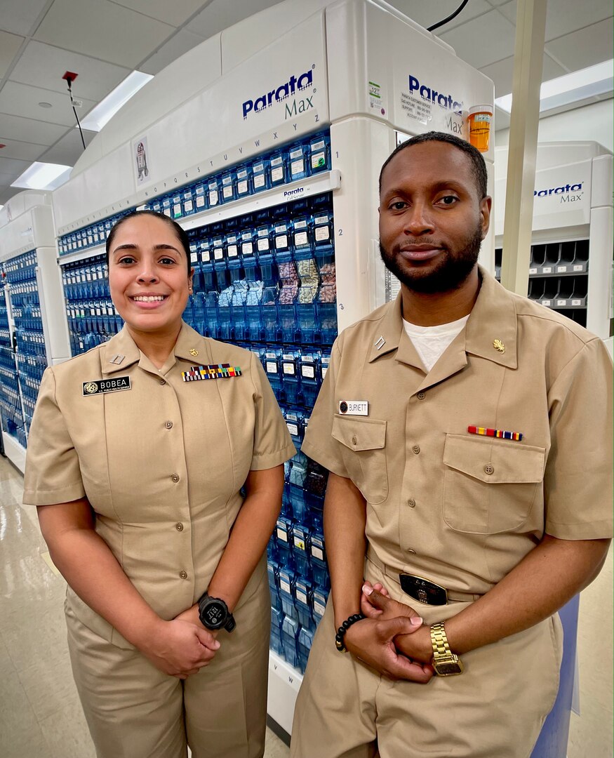 SAN DIEGO, Calif. (Jan. 12, 2024)  As Naval Medical Center San Diego (NMCSD) celebrates National Pharmacist Day, 12 Jan., we present two pharmacists whose parallel trajectory lead them to serving in one of the hospital’s most relied upon departments by beneficiaries who expect a precision and expediency that leaves zero room for complacency. Lt. Catherine Bobea, United States Public Health Service (USPHS) pharmacist serving at NMCSD and a native from Queens, New York City; and, Lt. Andre Burnett, NMCSD pharmacist and a native from Birmingham, Alabama, pose for an environmental photo in the pharmacy.
