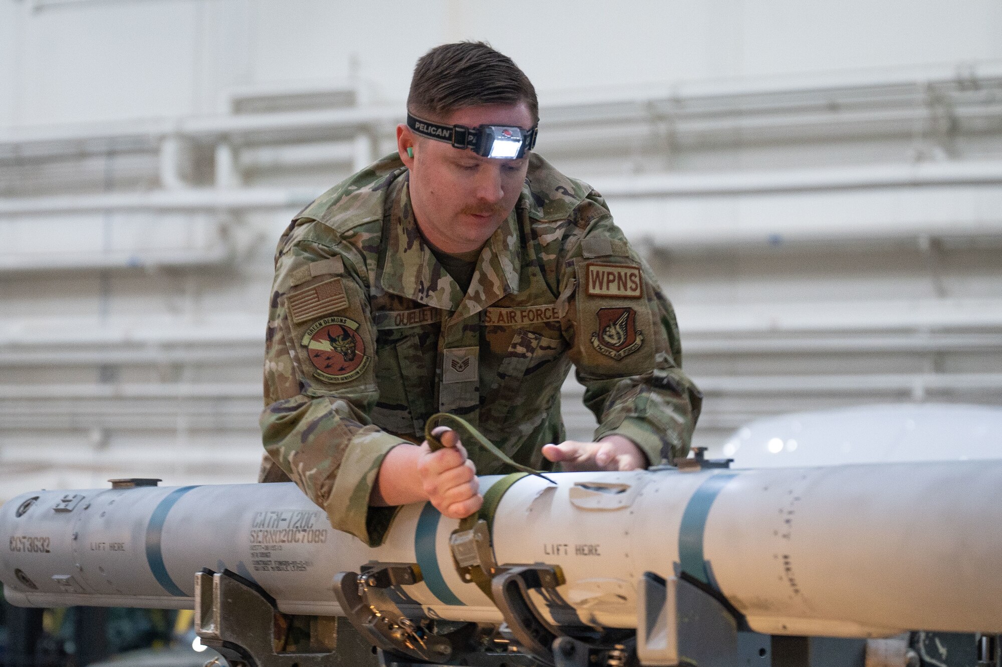 U.S. Air Force Staff Sgt. Christopher Ouellet, 356th Fighter Generation Squadron load crew team chief, pulls straps on a piece of armament during a load competition on Eielson Air Force Base, Alaska, Jan. 11, 2024.