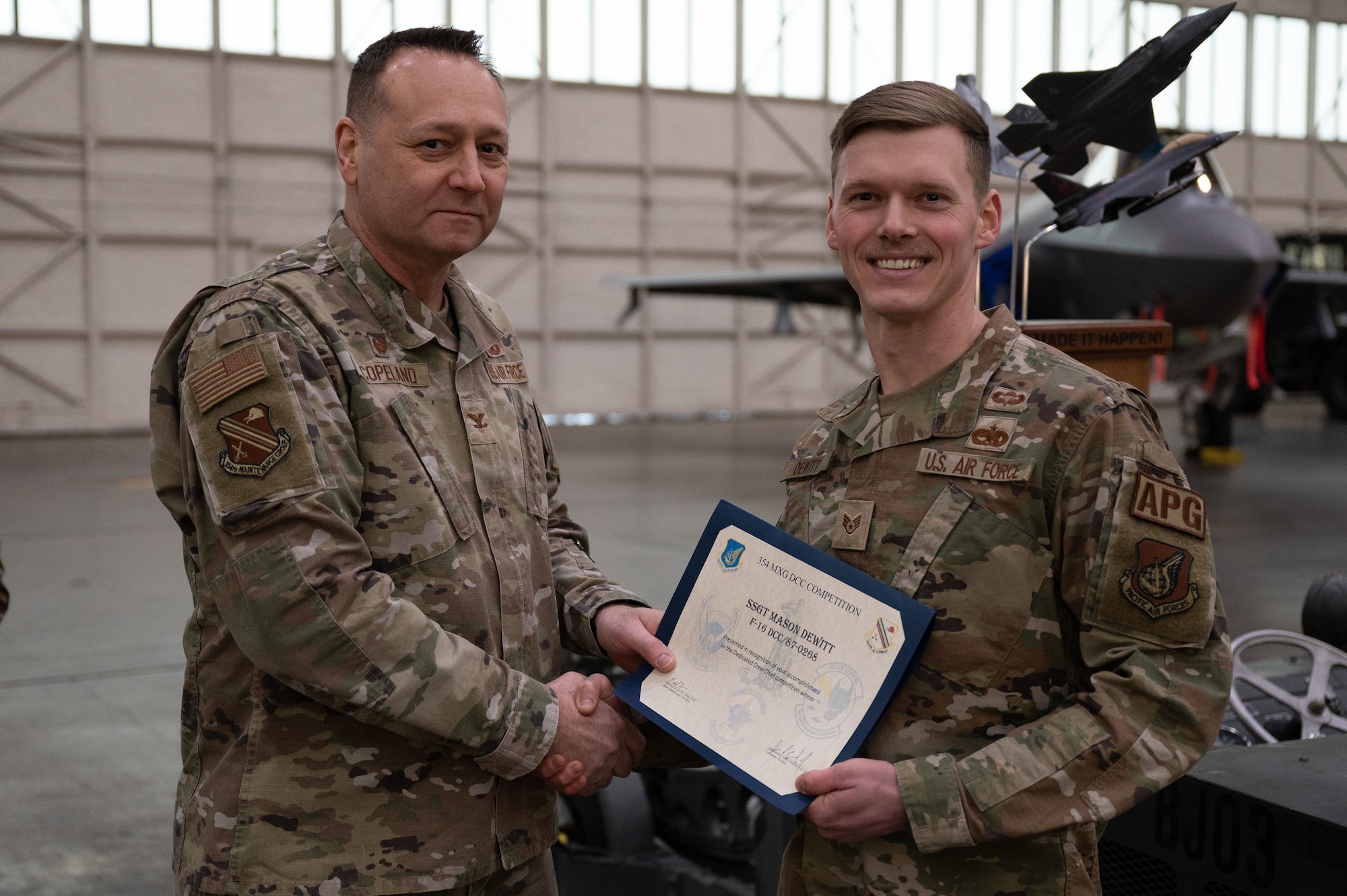 U.S. Air Force Col. Jerrymar Copeland (left), 354th Maintenance Group commander, hands a Dedicated Crew Chief award certificate to Staff Sgt. Mason Dewitt, 18th Aircraft Maintenance Unit dedicated crew chief, on Eielson Air Force Base, Alaska, Jan. 11, 2024.
