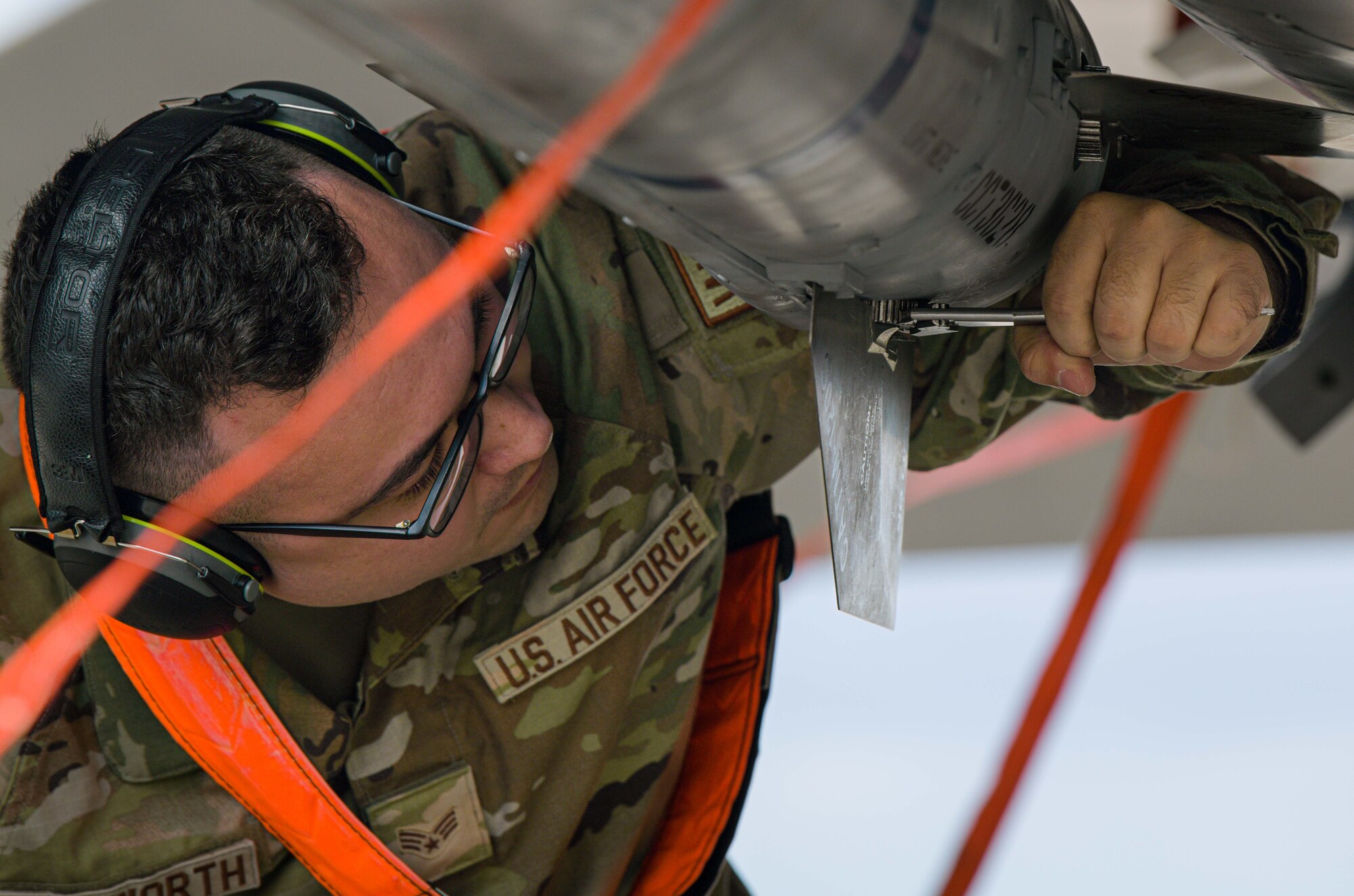 airman underneath aircraft turning wrench