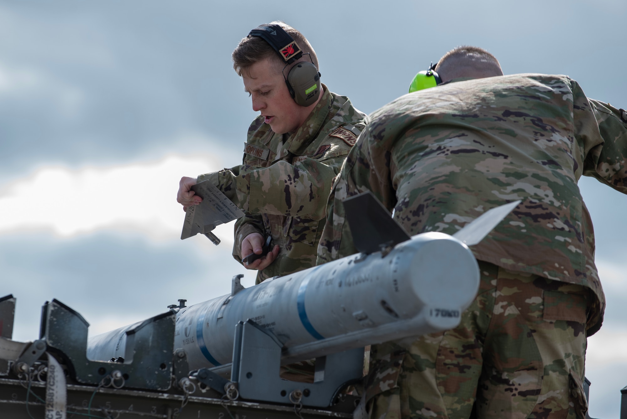 Airmen checks watch while loading munitions