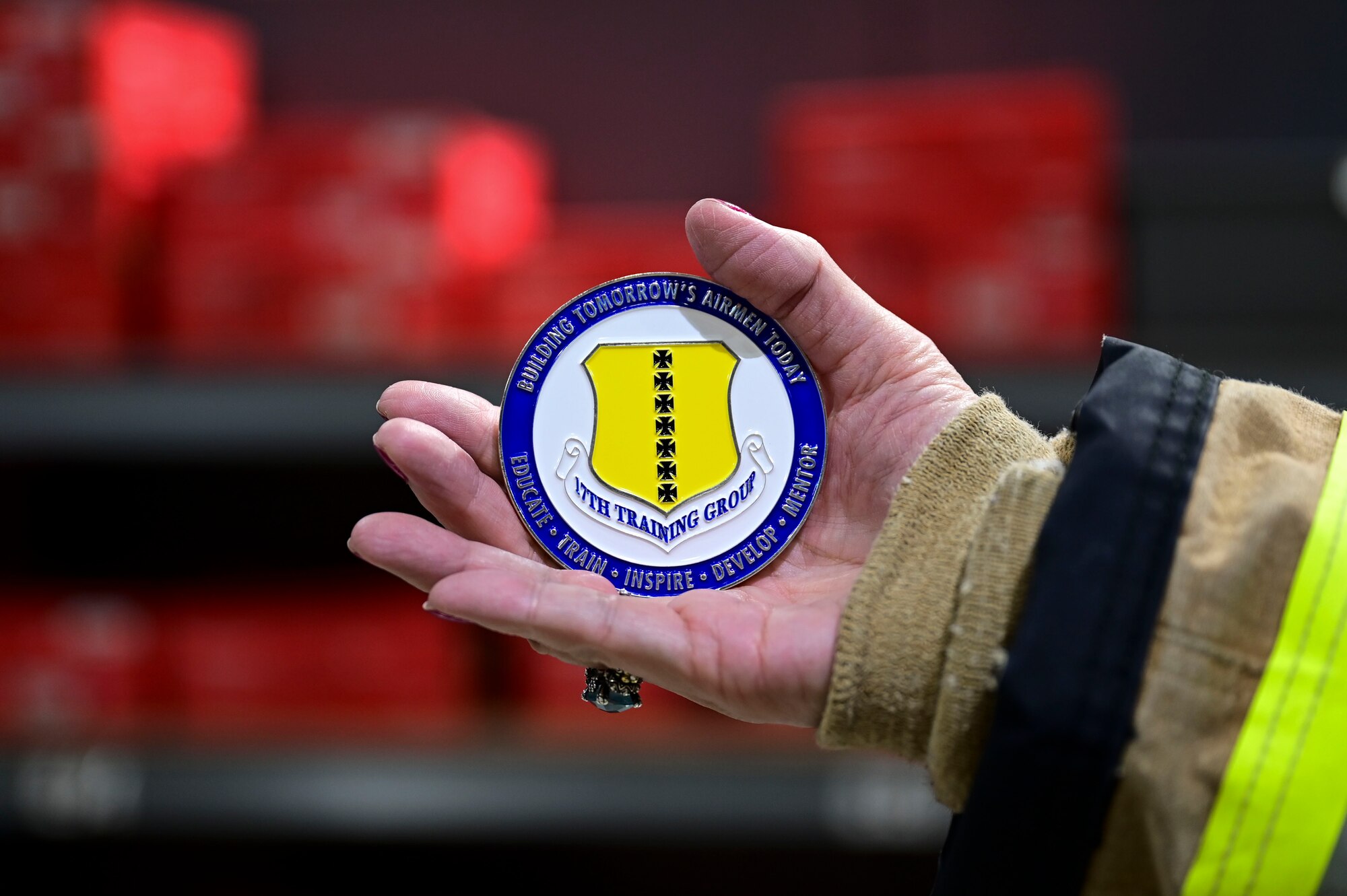 A coin presented by U.S. Air Force Col. Jason Kulchar,17th Training Group commander, is held by an honorary commander at the Louis F. Garland Department of the Defense Fire Academy, Goodfellow Air Force Base, Texas, Jan. 12, 2024. Their immersion with the 17th Training Group cumulated with a tour where Kulchar presented each honorary commander with a coin. Coins are a traditional keepsake given to those recognized by leadership for significant accomplishments. (U.S. Air Force photo by Airman 1st Class Madison Collier)