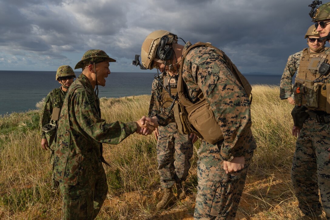 Japan Ground Self-Defense Force Maj. Gen. Shingo Nashinoki, commanding general of Amphibious Rapid Deployment Brigade, shakes hands with U.S. Marines with 5th Air Naval Gunfire Liaison Company, III Marine Expeditionary Force Information Group, during joint terminal attack controller training at Irisuna Island, Okinawa, Japan, Nov. 15, 2023. The training tested U.S. and Japanese service members’ ability to enhance and sustain tactics and procedures for terminal control of fires. 5th ANGLICO provides the Marine Air Ground Task Force Commander with a liaison capability to plan, coordinate, employ, and conduct terminal control of fires in support of joint, allied, and coalition forces.