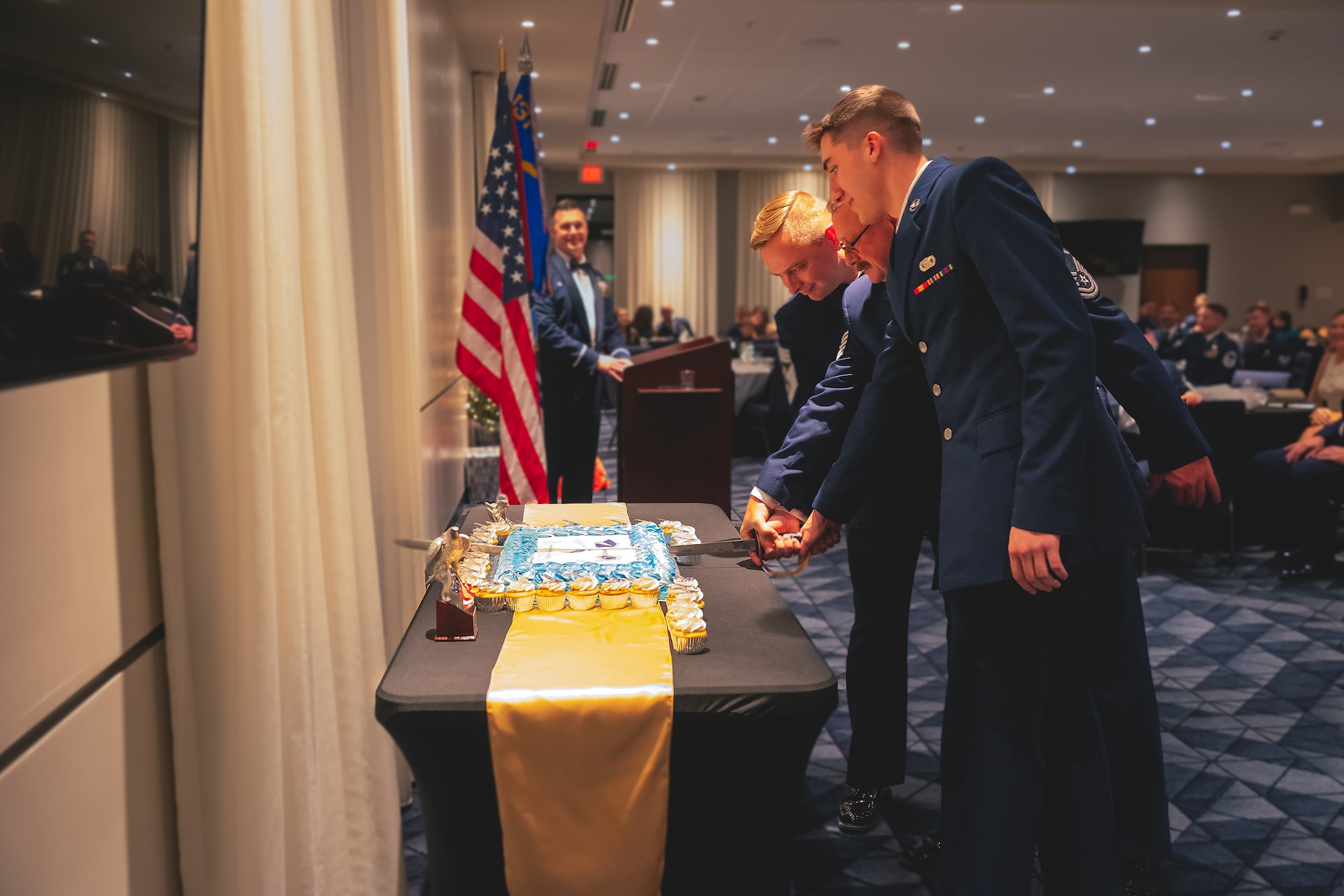 A group of Airmen perform a ceremonial cake-cutting with a saber during an awards banquet