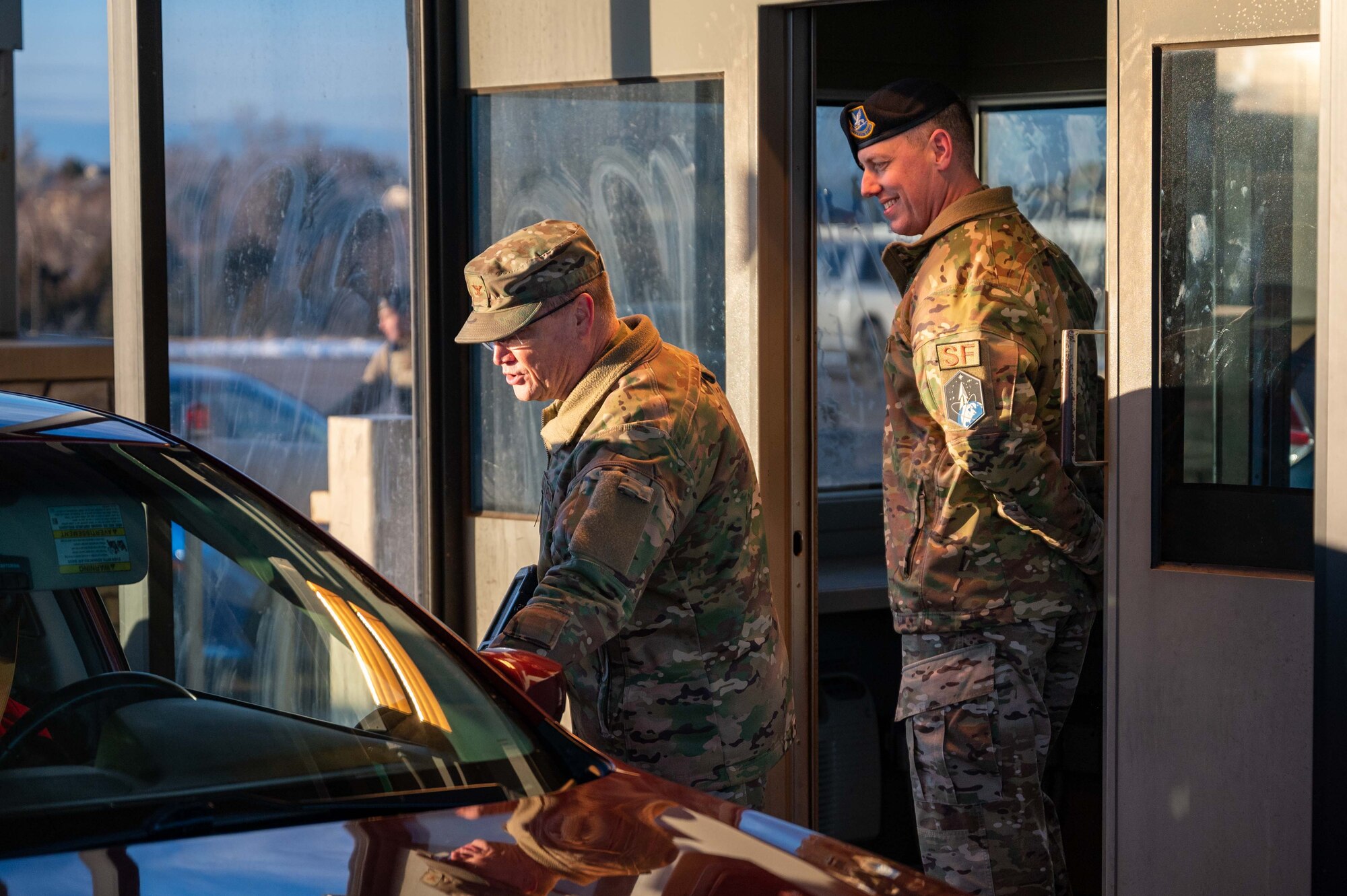 two men stand in front of vehicle.