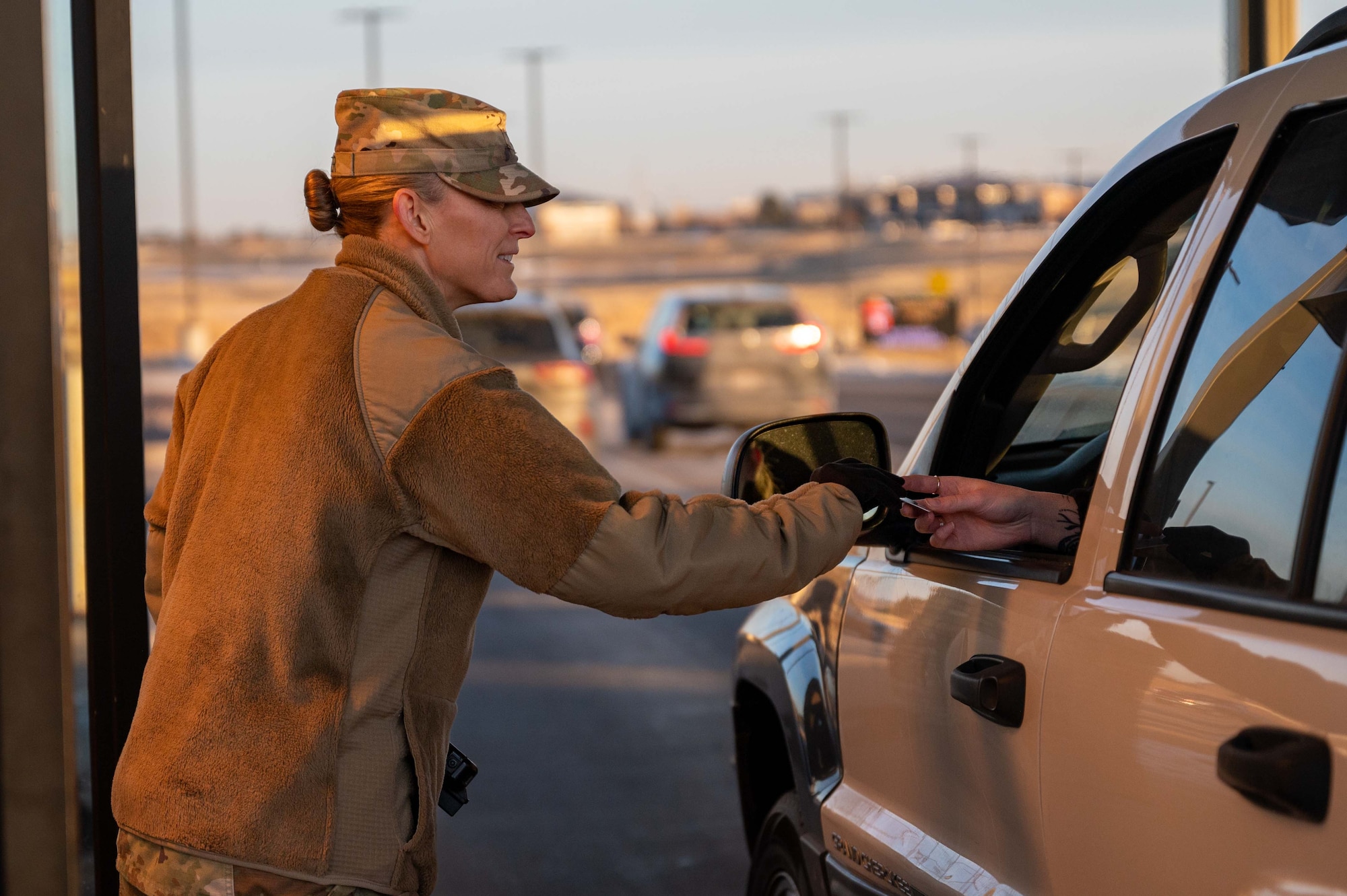 Woman hands card to person in vehicle.
