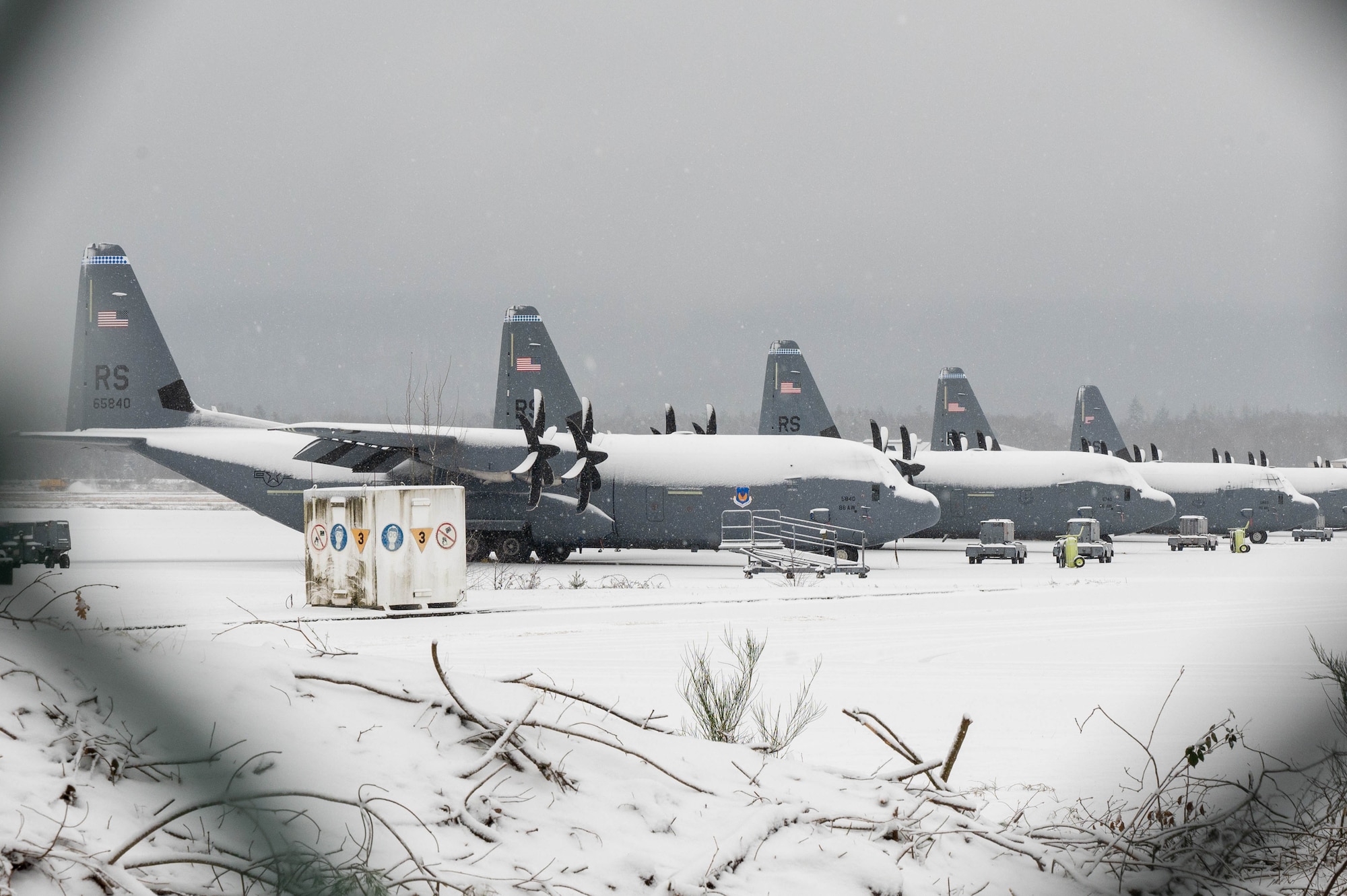 Five aircraft sit on the flightline as it snows