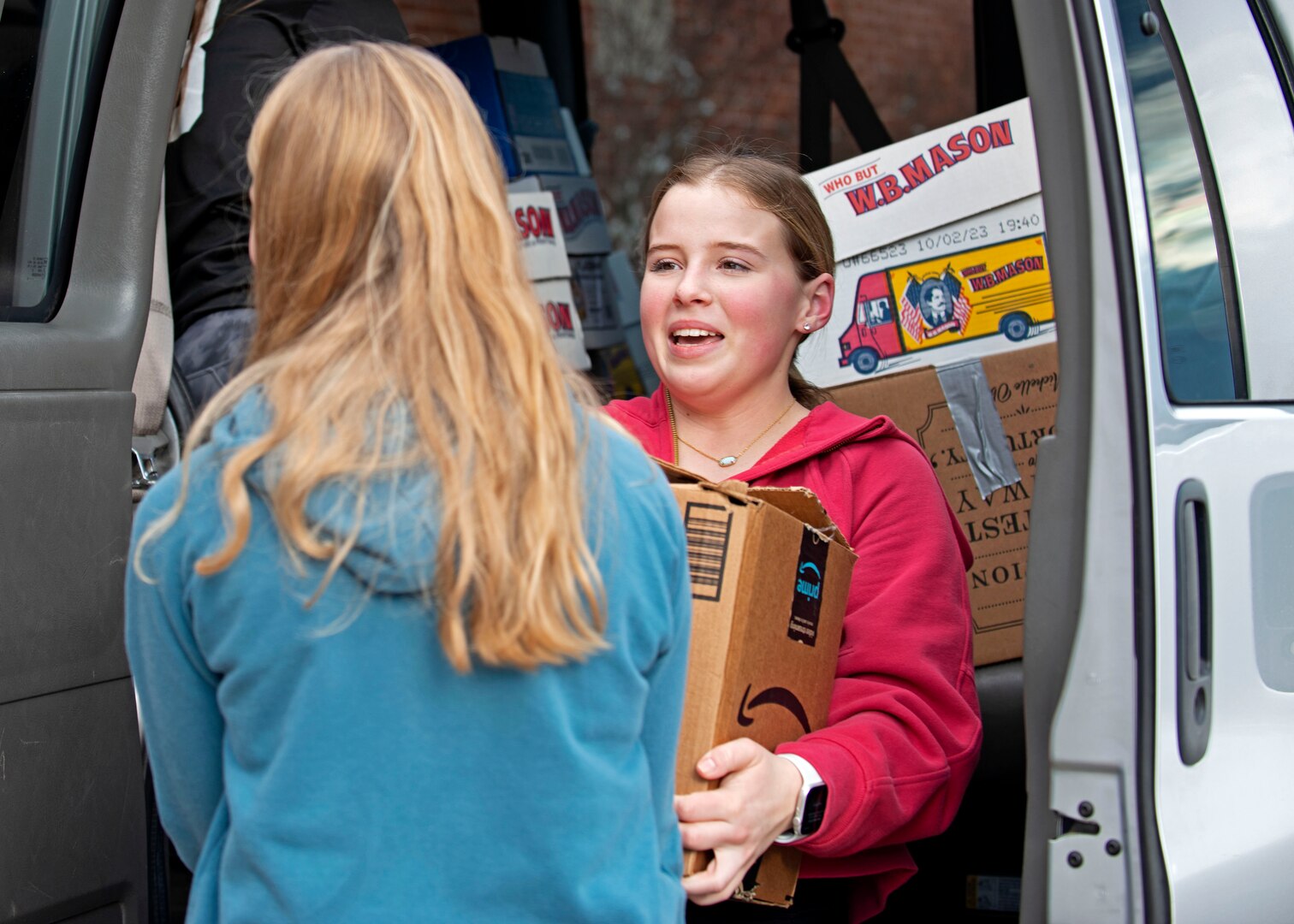 From left, ninth graders Charlotte Weiss and Stella Wantuck help load donated books into a cargo van Jan. 17, 2024, at Bow High School.