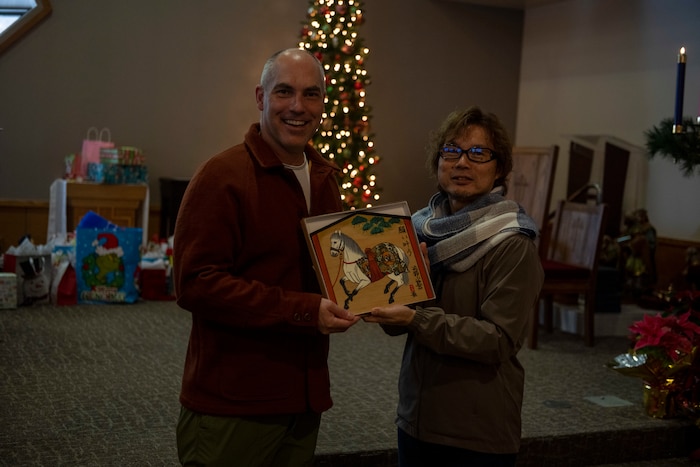 U.S. Air Force Lt. Col. Michael Carey, 35th Fighter Wing chaplain, receives a plaque from Mr. Tatsuya Goto, Biko-en Children's Care Facility director, during an Orphanage Angel Tree Gifts and Pool Party at Misawa Air Base, Japan, Dec. 16, 2023.