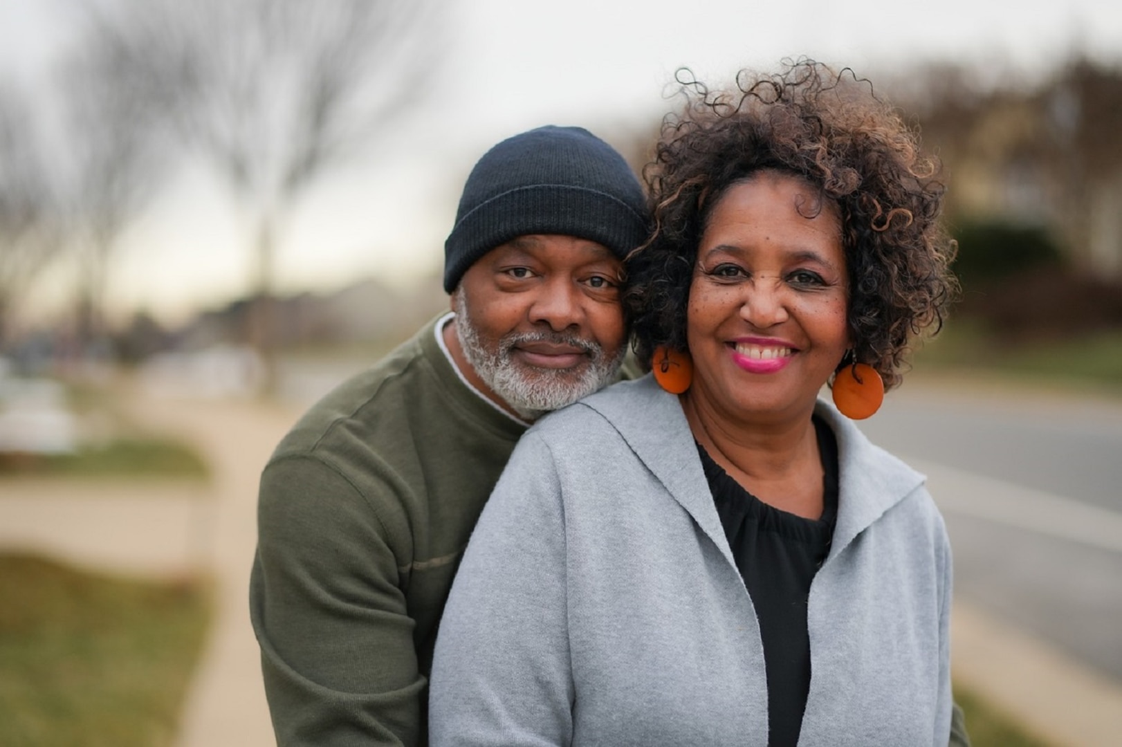 A senior couple smiles on a sidewalk.