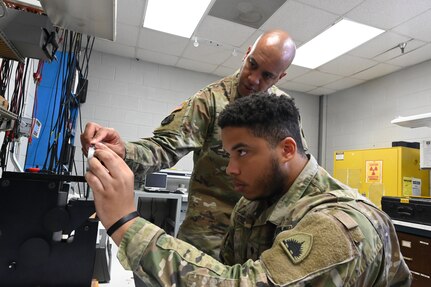 Sgt. 1st Class Andrew Sailes, District of Columbia National Guard Electronics and Calibration section supervisor, and Spc. John Parker, electronics and calibration technician, within the Test Measurement Diagnostic Equipment (TMDE) section, inspects a dial pressure gauge at the Surface Equipment Maintenance Facilities/Combined Support Maintenance Shop at Joint Base Anacostia-Bolling, Jan. 18, 2024. Standardized measurements ensure weapons systems from aircraft to mission-critical vehicles operate safely and effectively.