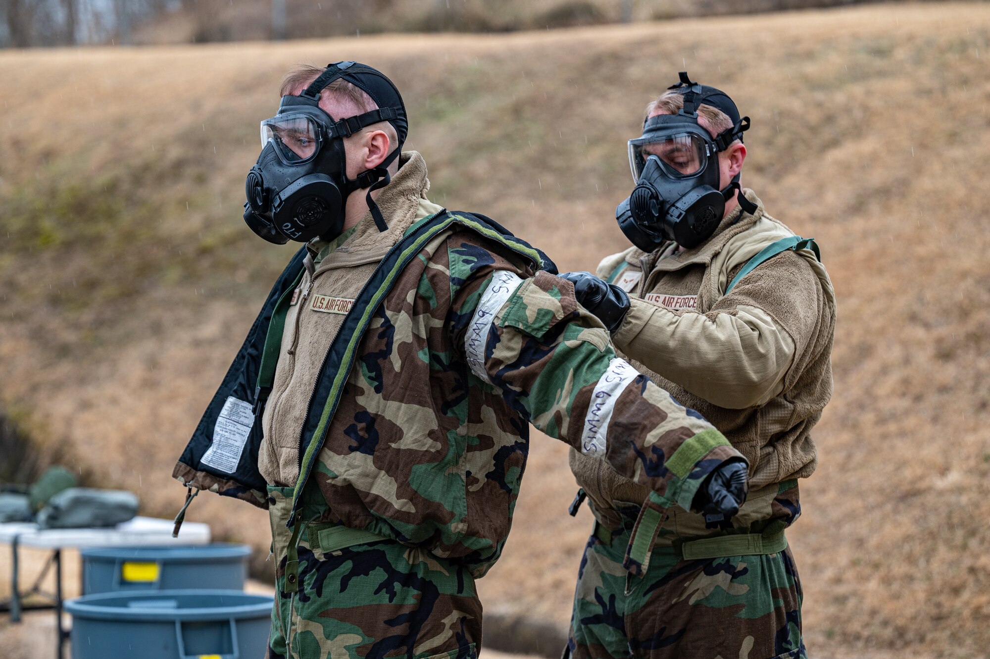 U.S. Air Force Airman 1st Class Rafe Russell, 51st Communications Squadron radio frequency technician, left, is assisted by Airman 1st Class Chase Verzaal, 51st Fighter Wing public affairs apprentice, in removing Mission Oriented Protective Posture Gear while practicing decontamination procedures during Shelter Management Training at Osan Air Base, Republic of Korea, Jan. 17, 2024. The decontamination process is designed to minimize the risk of contaminant exposure. It ensures that contaminants do not spread beyond the initial exposure area and maintains a safe environment for all personnel on base. (U.S. Air Force photo by Staff Sgt. Thomas Sjoberg)