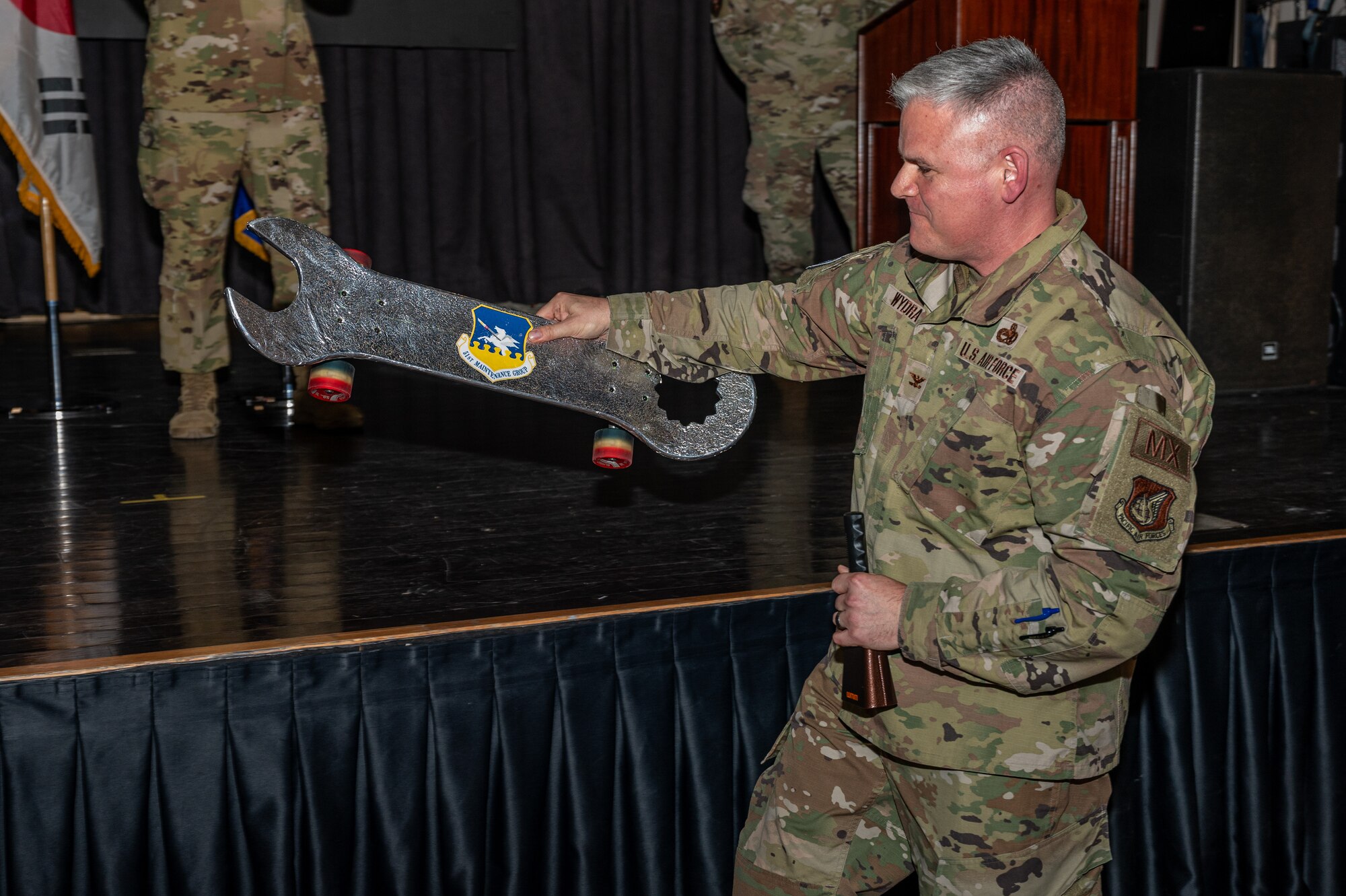 U.S. Air Force Col. Todd Wydra, 51st Maintenance Group commander, sets a skateboard on the stage during the 51st Fighter Wing quarterly awards ceremony at Osan Air Base, Republic of Korea, Jan. 19, 2024. Wing leadership regularly acknowledges outstanding performers, expressing appreciation for their contributions to the "Fight Tonight" mission. (U.S. Air Force photo by Airman 1st Class Chase Verzaal)