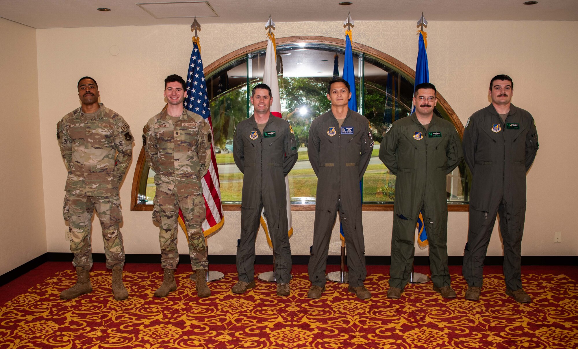 A group of service members stand at parade rest.