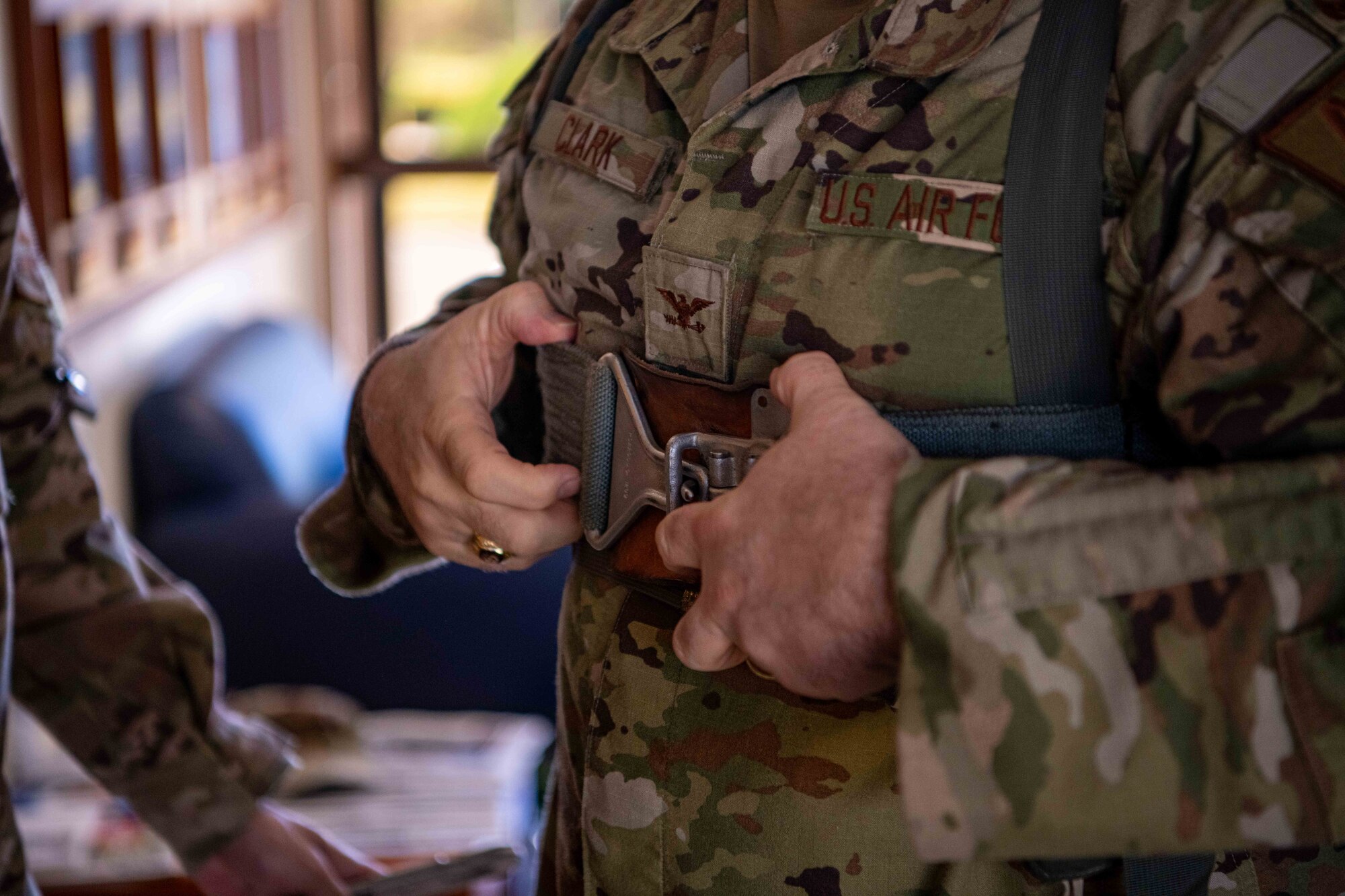 A close up shot of a service member buckling a harness.