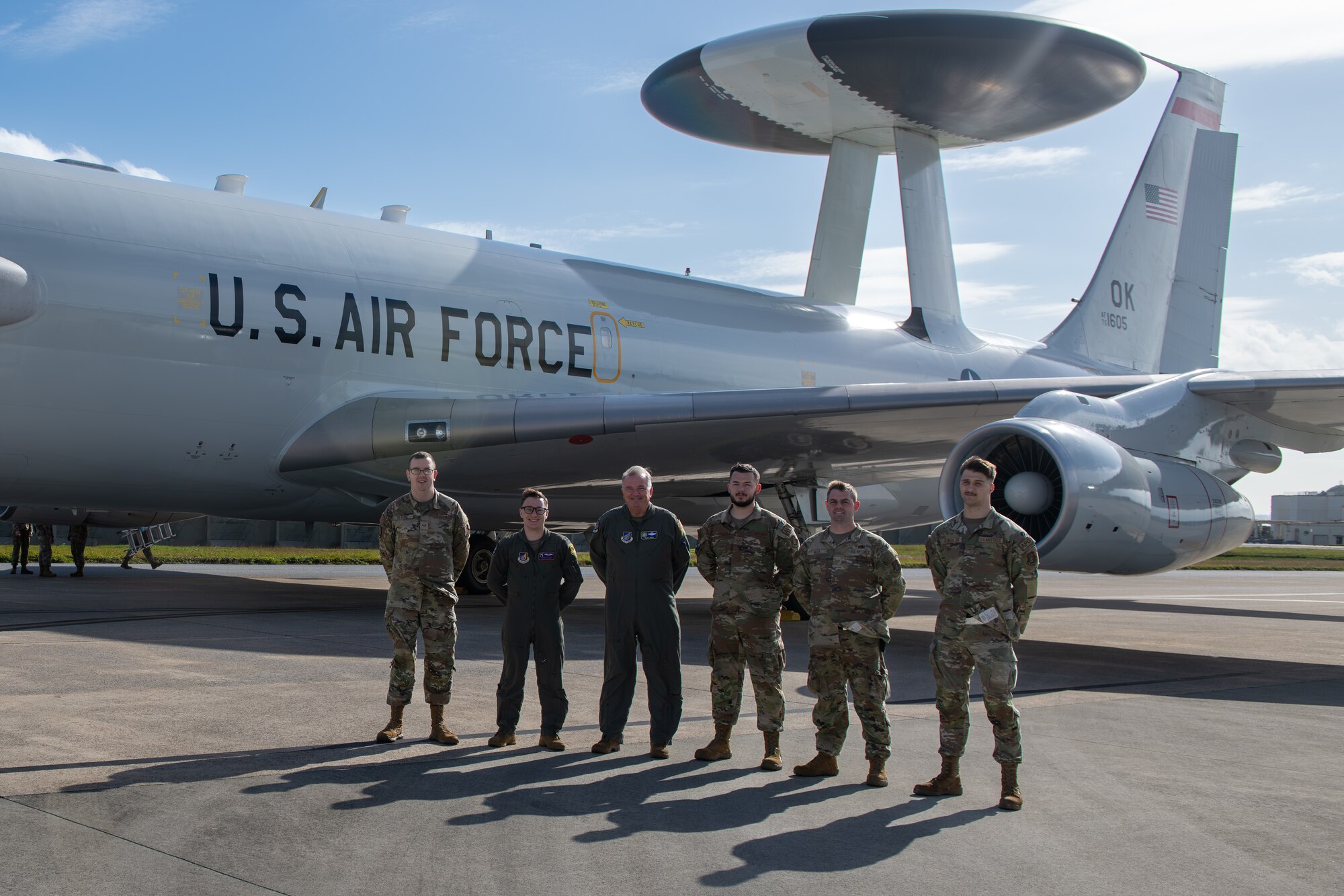 A group stands at parade rest in front of a plane.